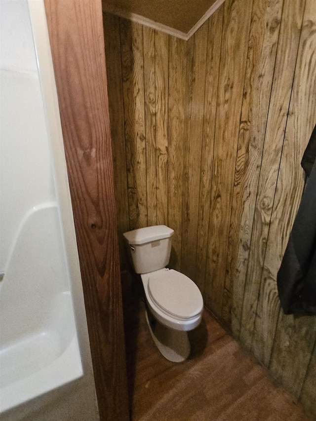 bathroom featuring crown molding, wood-type flooring, toilet, and wood walls