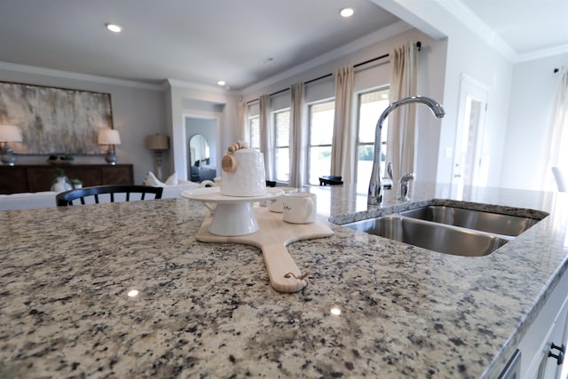 kitchen with recessed lighting, a sink, open floor plan, ornamental molding, and light stone countertops