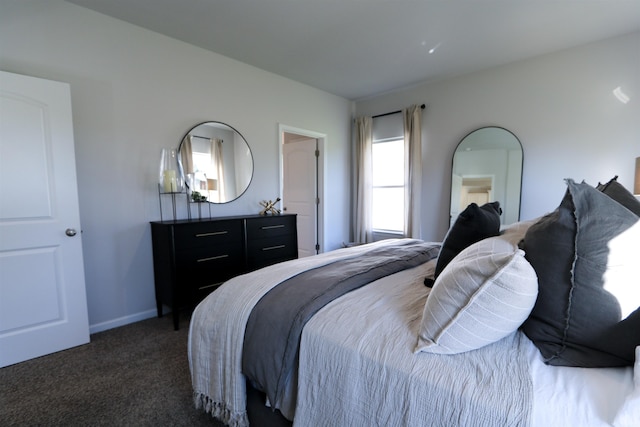 bedroom with dark colored carpet and baseboards