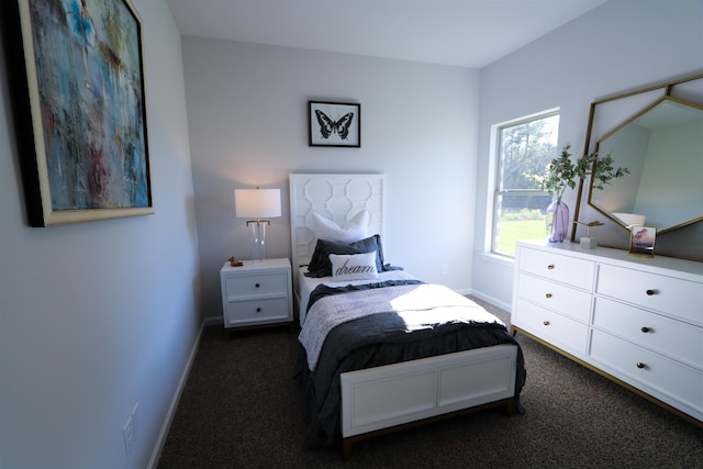 bedroom with dark colored carpet and baseboards