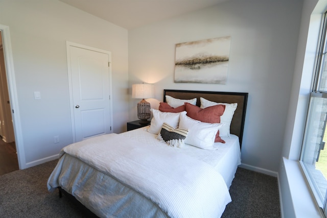 bedroom with dark carpet and baseboards