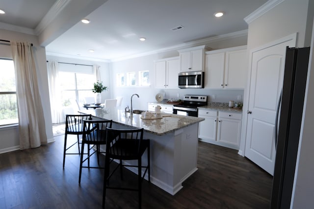 kitchen featuring appliances with stainless steel finishes, white cabinets, a sink, and an island with sink