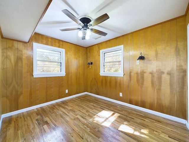 spare room featuring ceiling fan, wood walls, and hardwood / wood-style flooring