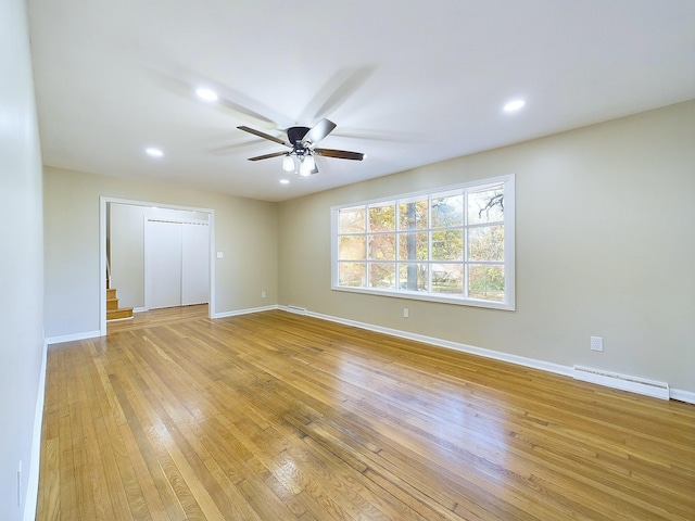 spare room featuring ceiling fan, light wood-type flooring, and a baseboard radiator