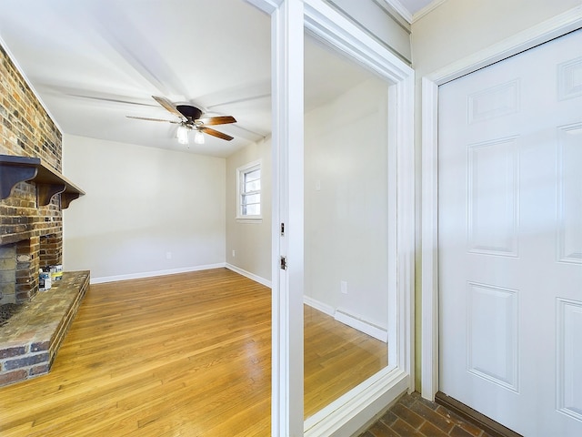 unfurnished living room featuring hardwood / wood-style floors, a baseboard radiator, a brick fireplace, and ceiling fan