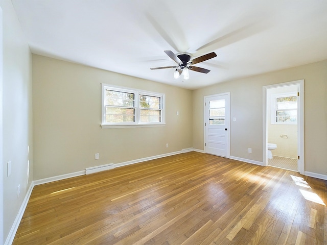 unfurnished bedroom featuring multiple windows, wood-type flooring, connected bathroom, and ceiling fan