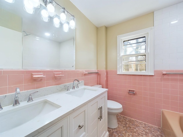 bathroom with a washtub, vanity, toilet, and tile walls