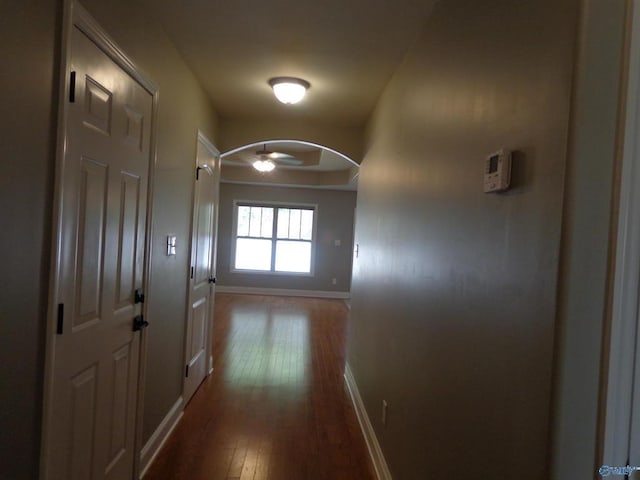  - hallway with baseboards, arched walkways, and dark wood-style flooring