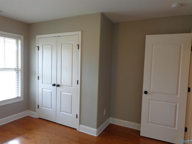  - unfurnished bedroom with multiple windows, baseboards, and wood finished floors