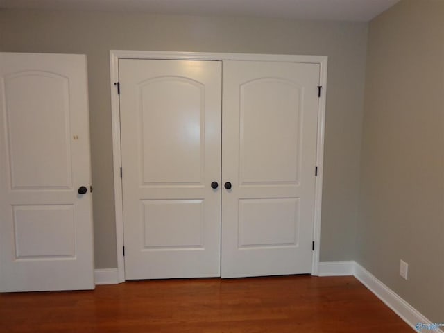  - unfurnished bedroom featuring wood finished floors, a closet, and baseboards
