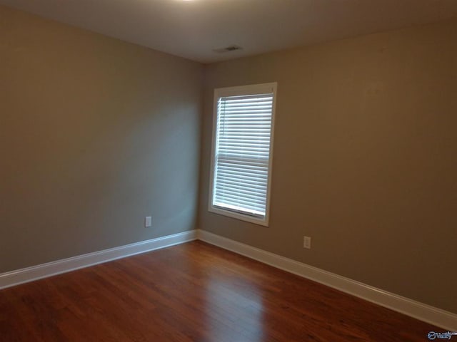  - spare room with visible vents, baseboards, and dark wood-style flooring