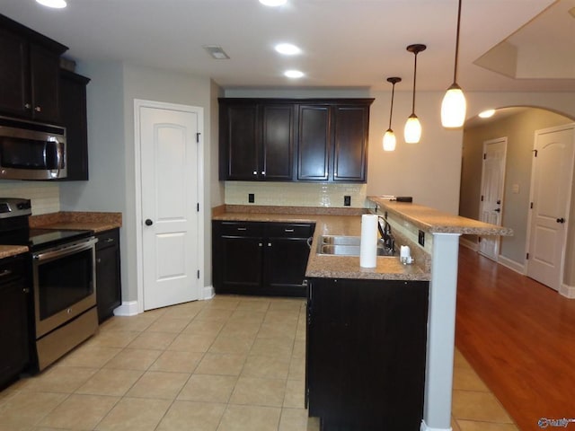  - kitchen featuring visible vents, a peninsula, arched walkways, stainless steel appliances, and a sink