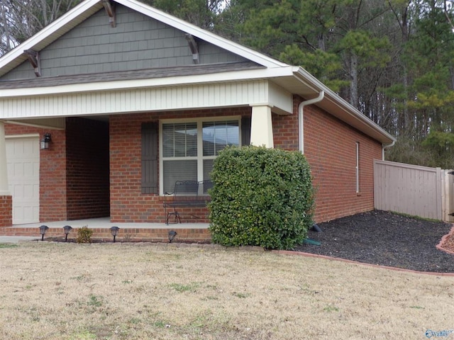  - view of home's exterior featuring brick siding, an attached garage, a porch, and fence