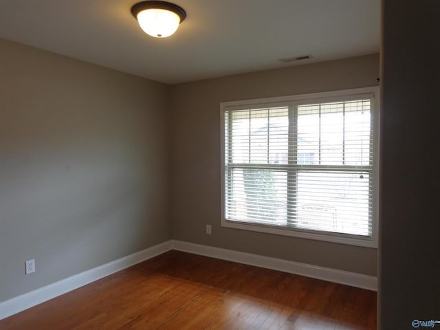  - empty room featuring visible vents, baseboards, and wood finished floors