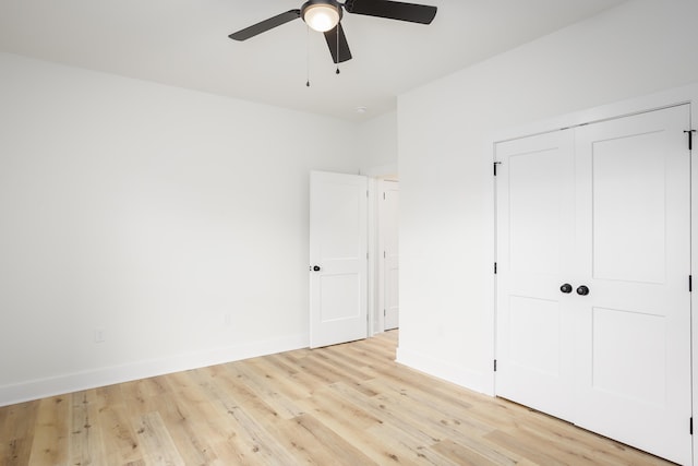 unfurnished bedroom with ceiling fan, light wood-type flooring, and a closet