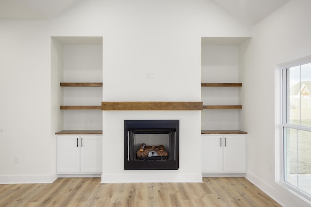 unfurnished living room with vaulted ceiling, light hardwood / wood-style floors, and a healthy amount of sunlight