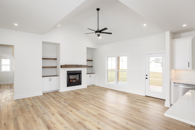 unfurnished living room featuring ceiling fan, high vaulted ceiling, light wood-type flooring, and built in shelves