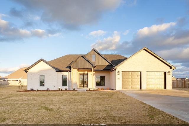 modern farmhouse style home with a garage, fence, driveway, a front lawn, and board and batten siding