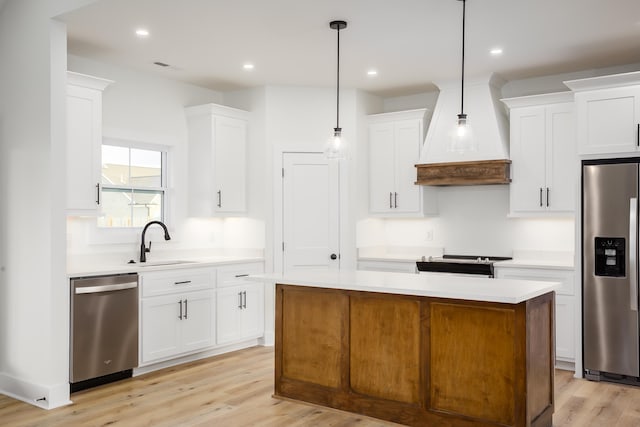 kitchen featuring sink, a center island, hanging light fixtures, stainless steel appliances, and white cabinets