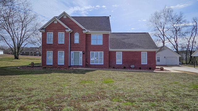 colonial house with a shingled roof, a front lawn, an outbuilding, and brick siding