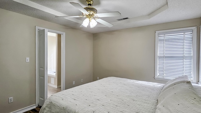 bedroom with a textured ceiling, multiple windows, connected bathroom, and visible vents