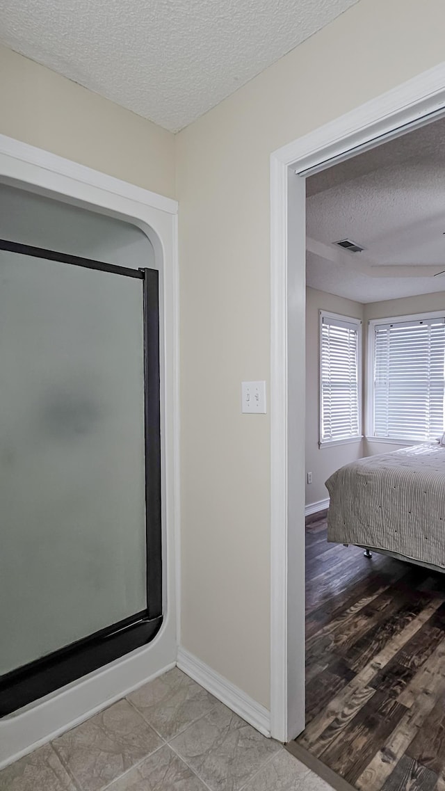 interior space featuring visible vents, a textured ceiling, baseboards, and wood finished floors