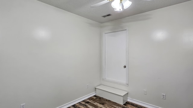 unfurnished room featuring a textured ceiling, visible vents, baseboards, a ceiling fan, and dark wood-style floors