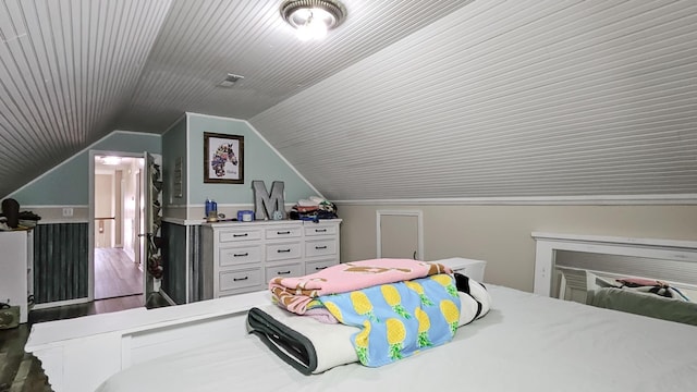 bedroom featuring crown molding, visible vents, vaulted ceiling, and wood finished floors