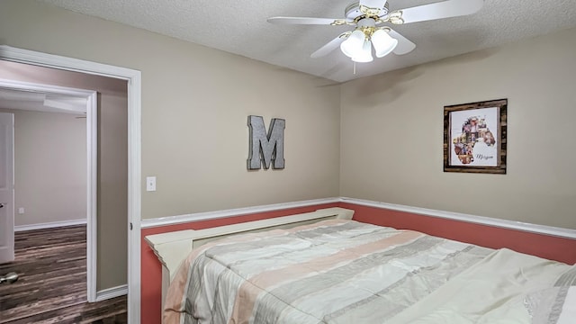 bedroom featuring ceiling fan, a textured ceiling, baseboards, and wood finished floors