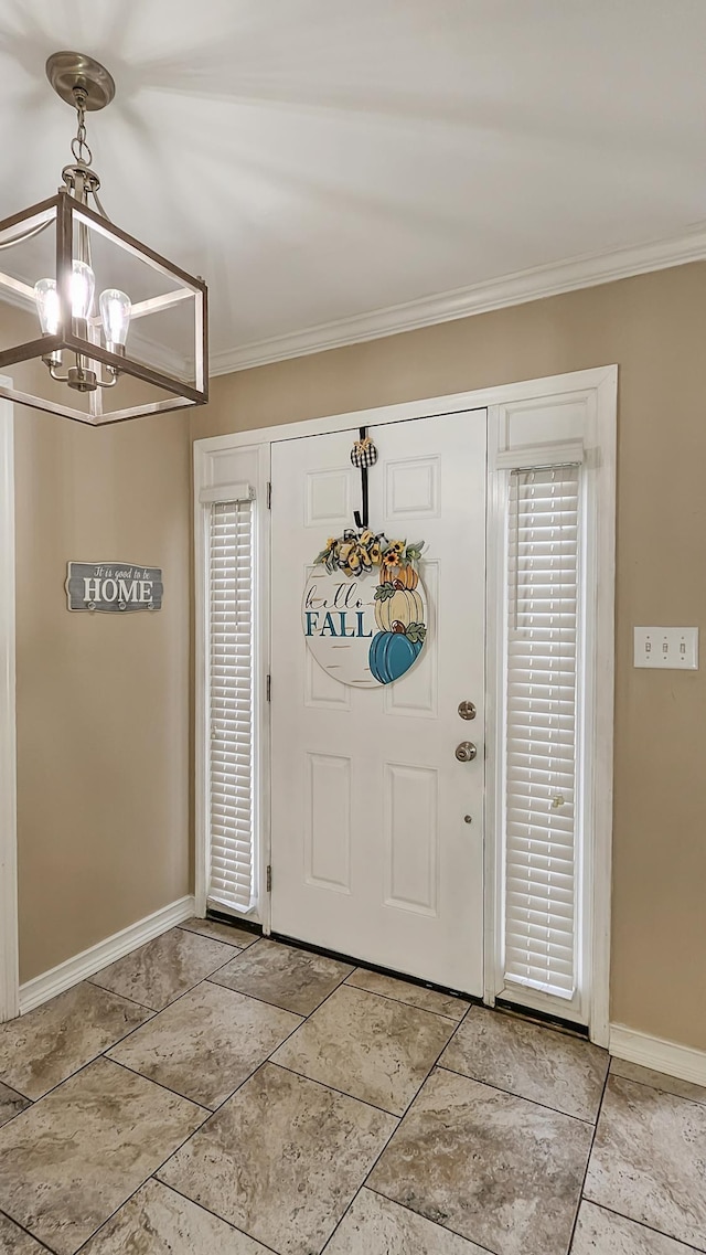 entrance foyer with a notable chandelier, ornamental molding, and baseboards