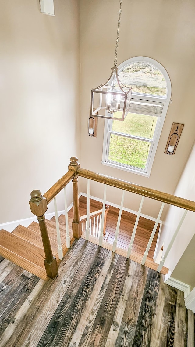 stairway with a notable chandelier, baseboards, and wood finished floors