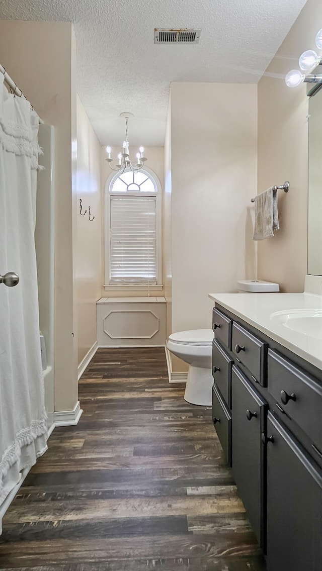 bathroom with visible vents, toilet, wood finished floors, a textured ceiling, and vanity