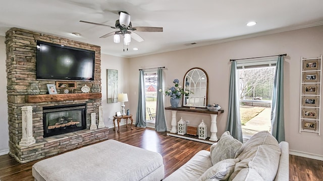 living room with visible vents, a healthy amount of sunlight, a stone fireplace, and wood finished floors