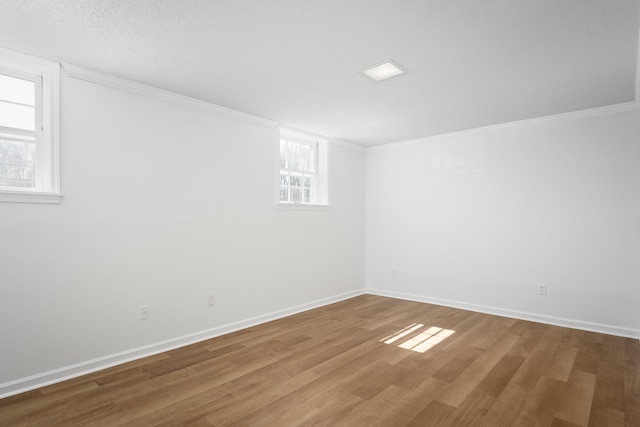 unfurnished room featuring crown molding, a textured ceiling, baseboards, and wood finished floors