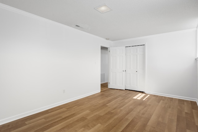 unfurnished bedroom featuring visible vents, crown molding, baseboards, and wood finished floors