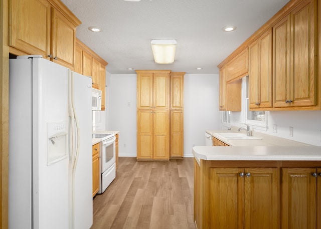 kitchen with light countertops, a sink, light wood-type flooring, white appliances, and a peninsula