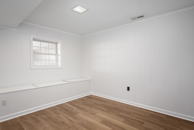 unfurnished room with visible vents, crown molding, baseboards, and wood finished floors