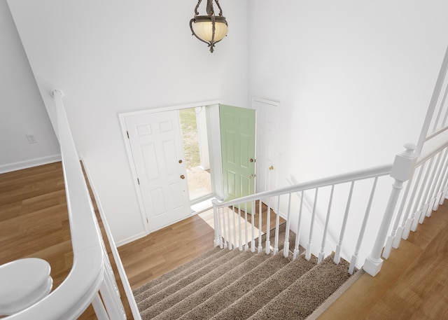 foyer featuring a towering ceiling, stairs, baseboards, and wood finished floors