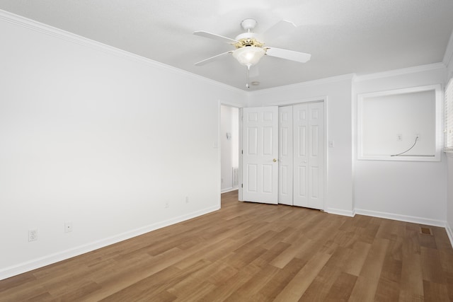 unfurnished bedroom featuring a ceiling fan, crown molding, baseboards, and wood finished floors