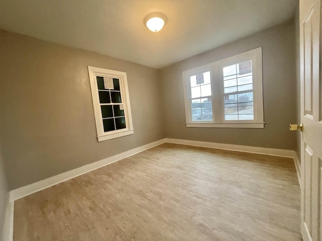 unfurnished room with light wood-type flooring and baseboards