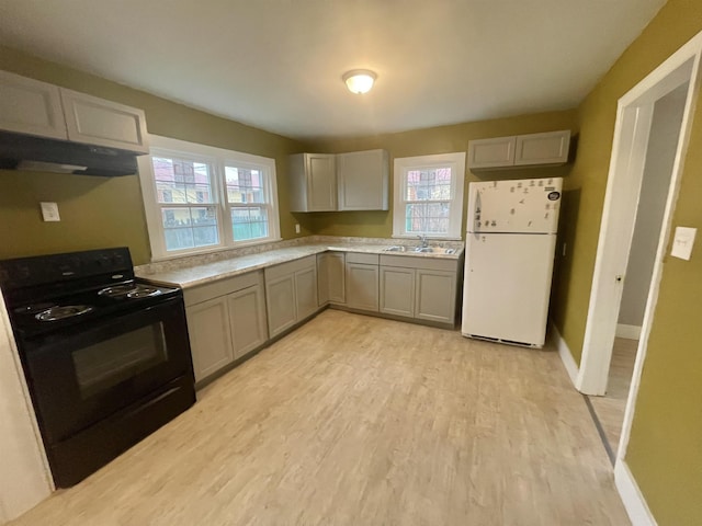 kitchen featuring a sink, light countertops, gray cabinets, freestanding refrigerator, and black electric range oven