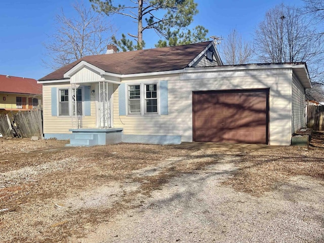 view of front facade featuring an attached garage, driveway, a chimney, and fence