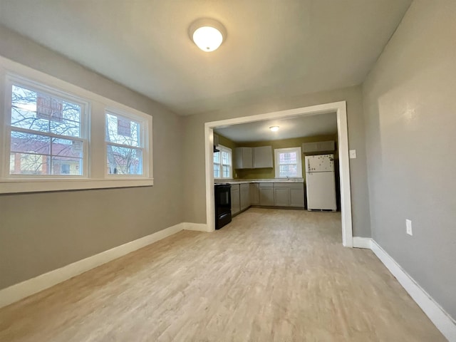 unfurnished living room with light wood-type flooring and baseboards