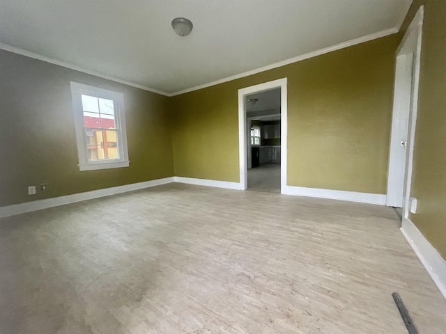 empty room featuring baseboards, light wood-style flooring, and crown molding