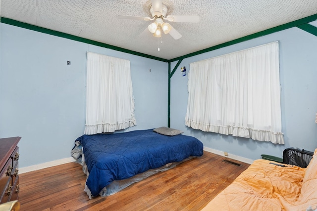 bedroom with hardwood / wood-style floors, a textured ceiling, and ceiling fan