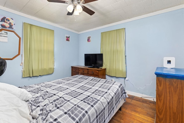 bedroom featuring dark wood-type flooring, ceiling fan, and crown molding