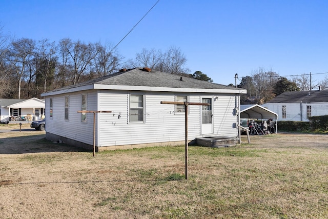 rear view of property featuring a yard and a carport