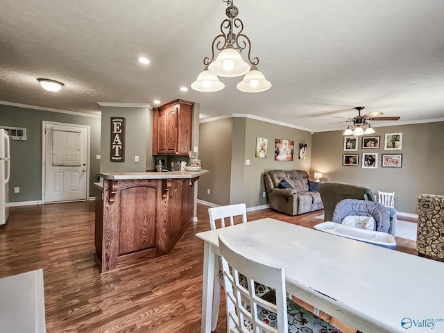 dining space featuring a textured ceiling, dark hardwood / wood-style flooring, ceiling fan, and ornamental molding