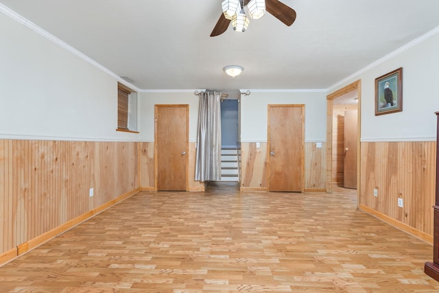 spare room featuring ornamental molding, wooden walls, and light wood-type flooring