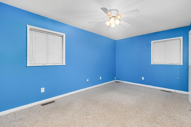 empty room with ceiling fan, carpet floors, and a textured ceiling